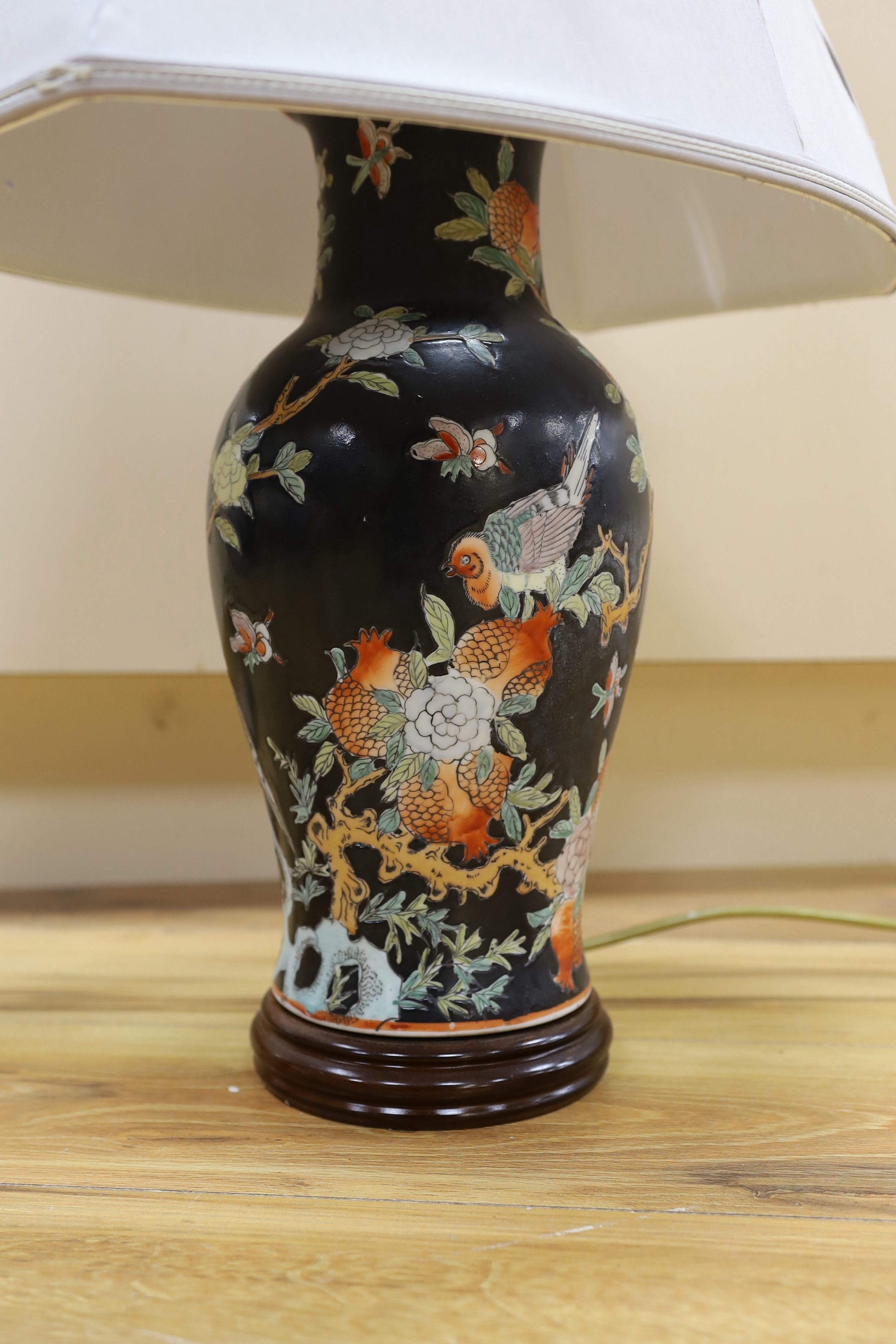 A Chinese famille noire table lamp and a pink ground Chinese vase, both on wooden stands, tallest vase 39cm